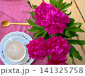 A bouquet of burgundy peonies, a coffee cup, and a porcelain set. 141325758