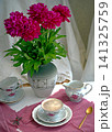 A bouquet of burgundy peonies, a coffee cup, and a porcelain set. 141325759