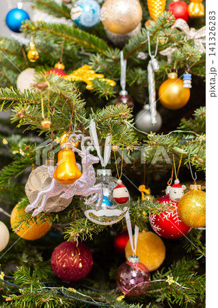 A Christmas tree stands with many colorful ornaments hanging from its branches. Each ornament shows different shapes and colors, celebrating the festive season and bringing joy to the home A Christmas tree stands with many colorful ornaments hanging from its branches. Each ornament shows different shapes and colors, celebrating the festive season and bringing joy to the home 141326283