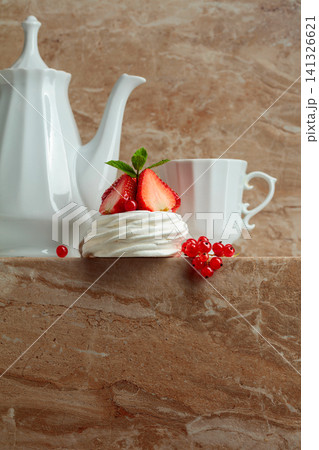 Pavlova dessert with strawberries, red currant, and mint on a beige table. 141326621