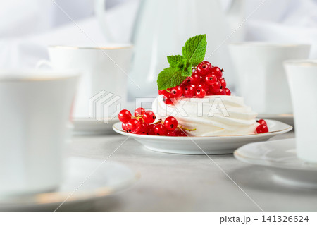Pavlova dessert with red currant, and mint on a white table. Pavlova dessert with red currant, and mint on a white table. 141326624