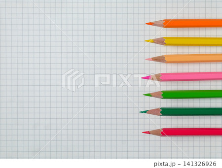 Color pencils on empty grid paper, top view. Color pencils on empty grid paper, top view. 141326926