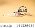 A measuring tape around magnifying glass and text SLIM . 141326939