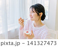 朝食でヨーグルトを食べる若い女性 朝食でヨーグルトを食べる若い女性 141327473