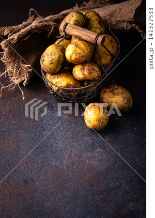 Raw uncooked potato on dark background Raw uncooked potato on dark background 141327533