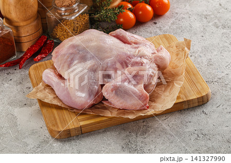 Raw whole chicken on wooden cutting board with spices and tomatoes 141327990