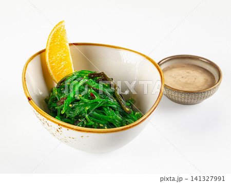Fresh seaweed salad with orange slice and dipping sauce in ceramic bowls Fresh seaweed salad with orange slice and dipping sauce in ceramic bowls 141327991