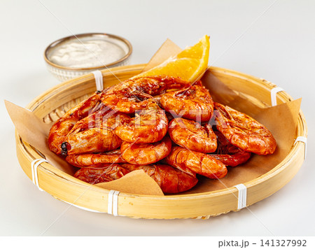 Spicy glazed shrimp in bamboo basket with citrus wedge and dipping sauce 141327992