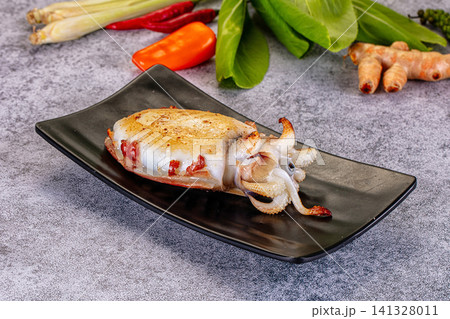 Grilled squid on black plate with fresh herbs and spices Grilled squid on black plate with fresh herbs and spices 141328011