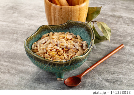 Roasted peanuts in ceramic bowl with wooden spoon and bay leaves Roasted peanuts in ceramic bowl with wooden spoon and bay leaves 141328018