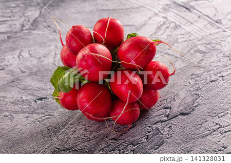Fresh red radishes with green leaves on textured gray surface 141328031