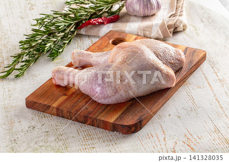 Raw chicken legs on wooden cutting board with rosemary garlic and chili Raw chicken legs on wooden cutting board with rosemary garlic and chili 141328035