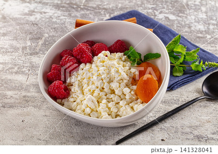 Cottage cheese bowl with raspberries apricots and mint on rustic surface 141328041