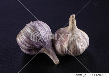 Two purple striped garlic bulbs on dark textured background Two purple striped garlic bulbs on dark textured background 141328067