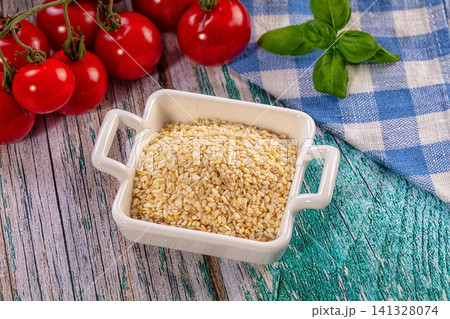 Sesame seeds in white ceramic bowl with cherry tomatoes and basil on rustic wooden table Sesame seeds in white ceramic bowl with cherry tomatoes and basil on rustic wooden table 141328074