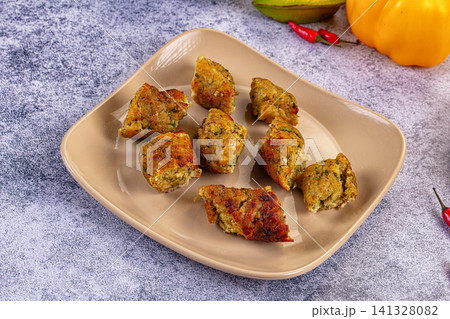 Grilled chicken kebab pieces on beige plate with colorful vegetables 141328082