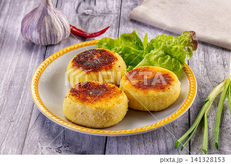 Golden fried cheese cakes with fresh greens and garlic on rustic plate Golden fried cheese cakes with fresh greens and garlic on rustic plate 141328153