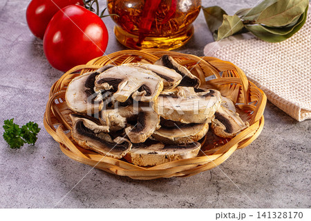 Dried sliced mushrooms in a wicker basket with fresh tomatoes and infused oil on a grey background Dried sliced mushrooms in a wicker basket with fresh tomatoes and infused oil on a grey background 141328170