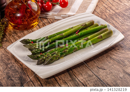 Fresh green asparagus spears on white plate with sea salt and red peppercorns Fresh green asparagus spears on white plate with sea salt and red peppercorns 141328219