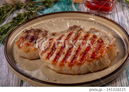 Grilled pork chop with rosemary and sauce on ceramic plate Grilled pork chop with rosemary and sauce on ceramic plate 141328225