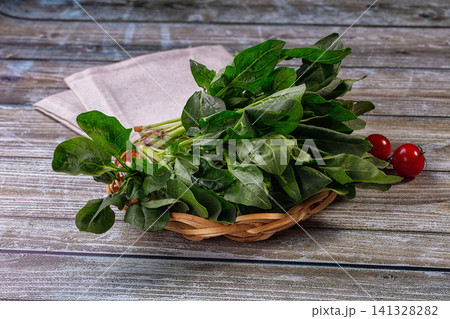 Fresh spinach leaves in woven basket with cherry tomatoes on rustic wooden table Fresh spinach leaves in woven basket with cherry tomatoes on rustic wooden table 141328282