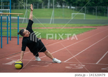 muscular young athlete has workout and exercising with medicine ball outdoor muscular young athlete has workout and exercising with medicine ball outdoor 141328479