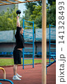 young athlete has workout and doing sport exercises with kettlebell outdoor 141328493