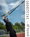 yound sporty athlete or bodybuilder has fitness workout with trx outdoor 141328495