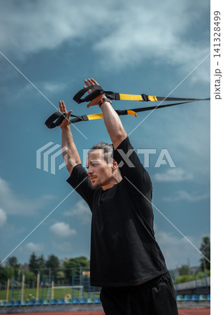 yound sporty athlete or bodybuilder has fitness workout with trx outdoor 141328499