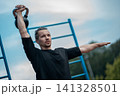 young athlete has workout and doing sport exercises with kettlebell outdoor 141328501