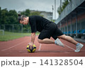 muscular young athlete has workout and exercising with medicine ball outdoor 141328504