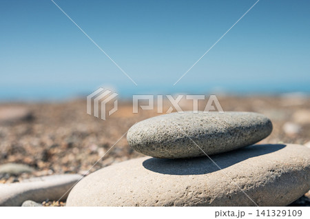Smooth stones stacked on blurred beach under clear summer sky. Smooth stones stacked on blurred beach under clear summer sky. 141329109