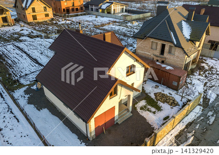 Aerial view of new residential house cottage and attached garage with shingle roof on fenced yard on sunny winter day in modern suburban area. Perfect investment in dream house. Aerial view of new residential house cottage and attached garage with shingle roof on fenced yard on sunny winter day in modern suburban area. Perfect investment in dream house. 141329420