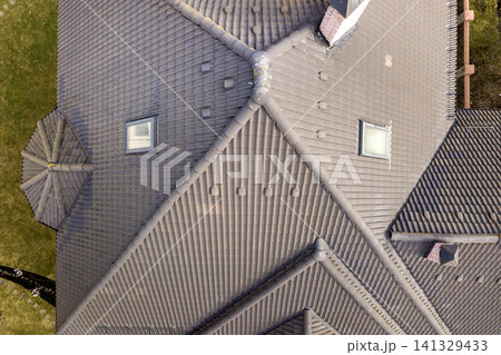 Aerial view of house roof top covered with ceramic shingles. Tiled covering of building under construction 141329433