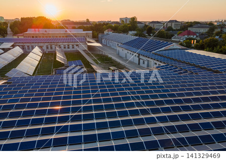 Aerial view of blue photovoltaic solar panels mounted on industrial building roof for producing green ecological electricity. Production of sustainable energy concept Aerial view of blue photovoltaic solar panels mounted on industrial building roof for producing green ecological electricity. Production of sustainable energy concept 141329469