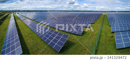 Aerial view of big sustainable electric power plant with many rows of solar photovoltaic panels for producing clean electrical energy. Renewable electricity with zero emission concept Aerial view of big sustainable electric power plant with many rows of solar photovoltaic panels for producing clean electrical energy. Renewable electricity with zero emission concept 141329472