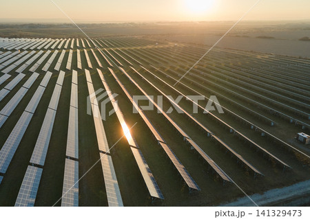 Aerial view of big sustainable electric power plant with many rows of solar photovoltaic panels for producing clean electrical energy at sunset. Renewable electricity with zero emission concept Aerial view of big sustainable electric power plant with many rows of solar photovoltaic panels for producing clean electrical energy at sunset. Renewable electricity with zero emission concept 141329473