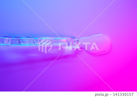 Cosmetic serum dropper dispensing liquid on vibrant background 141330157
