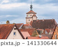 Clock tower and red tiled rooftops in Rothenburg ob der Tauber under cloudy sky, Germany 141330644