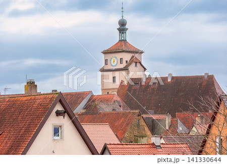 Clock tower and red tiled rooftops in Rothenburg ob der Tauber under cloudy sky, Germany Clock tower and red tiled rooftops in Rothenburg ob der Tauber under cloudy sky, Germany 141330644