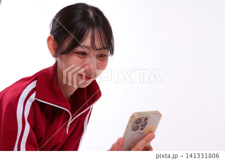 スマホを見るジャージの女性 スマホを見るジャージの女性 141331806