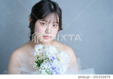 グレー背景でブーケを抱えて見つめるウェディングドレスの日本人女性 グレー背景でブーケを抱えて見つめるウェディングドレスの日本人女性 141332679