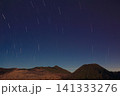 mountain landscape beneath a spectacular night sky filled with circular star trails, capturing the Earth's rotation and beauty of long exposure photography for travel promotion, astronomy publication 141333276