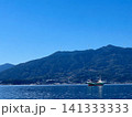 穏やかな海に浮かぶ貨物船と風力発電のある山並み 141333333