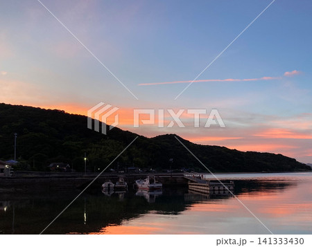 夕焼けに染まる静かな港と茜色の穏やかな海 夕焼けに染まる静かな港と茜色の穏やかな海 141333430