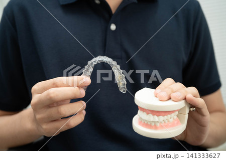 Man holding invisible aligner orthodontic retainer for dental teeth straightening. Man holding invisible aligner orthodontic retainer for dental teeth straightening. 141333627