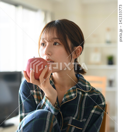 パジャマ姿の女性がリンゴを食べる朝のくつろぎタイム パジャマ姿の女性がリンゴを食べる朝のくつろぎタイム 141333773