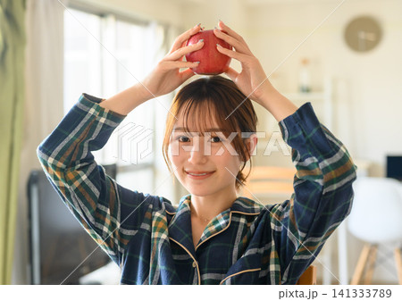 リンゴを頭に乗せるパジャマ姿の女性、自然光あさの自然光 リンゴを頭に乗せるパジャマ姿の女性、自然光あさの自然光 141333789
