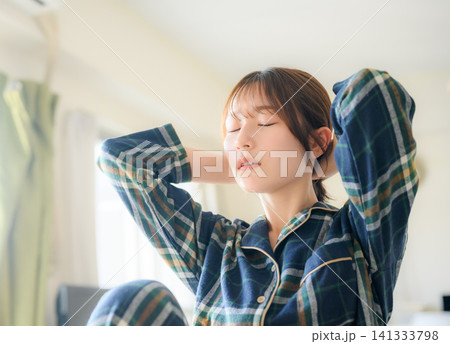 パジャマ姿でストレッチする女性、リラックスした休日 パジャマ姿でストレッチする女性、リラックスした休日 141333798