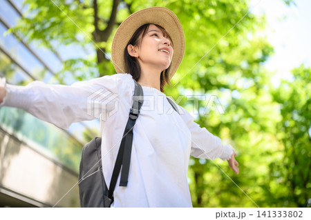 リュックを背負い麦わら帽子をかぶった女性、新緑の中を楽しむ った女性、新緑の中、楽しそうに 両手を広 141333802
